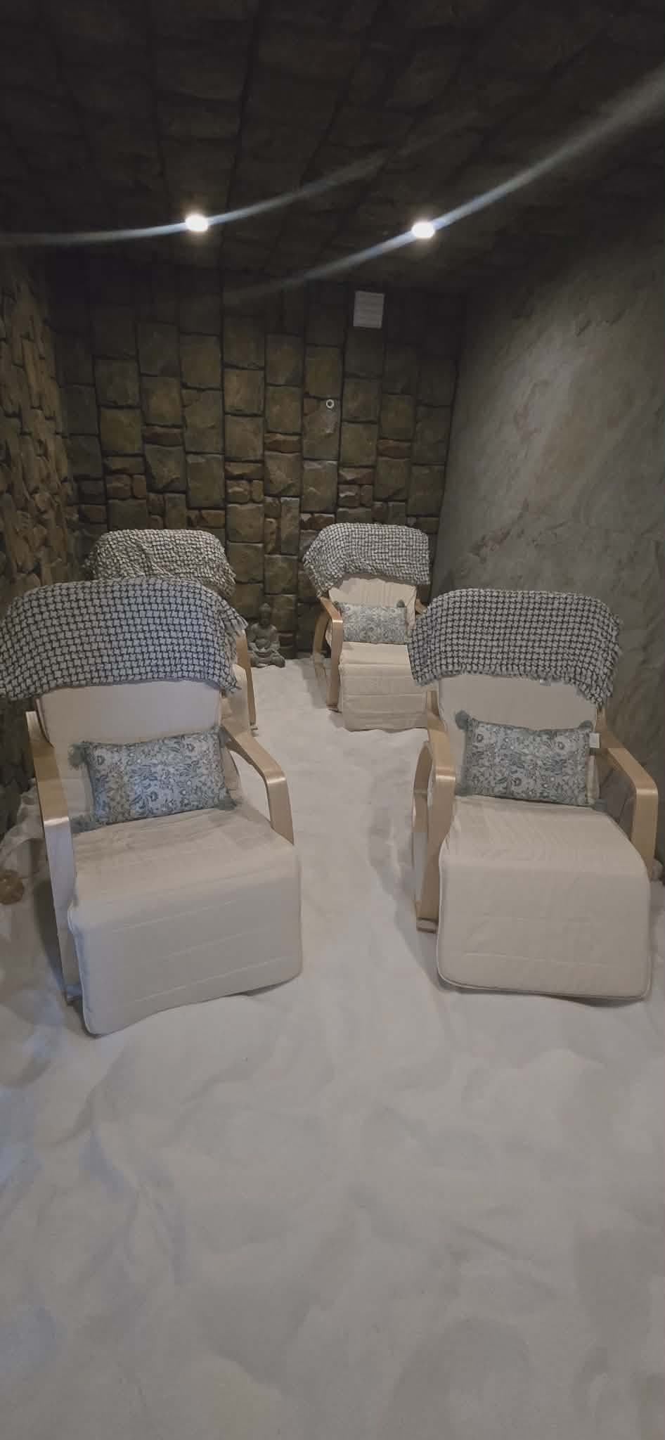 Salt room featuring reclining chairs with blankets and pillows on a white salt floor.